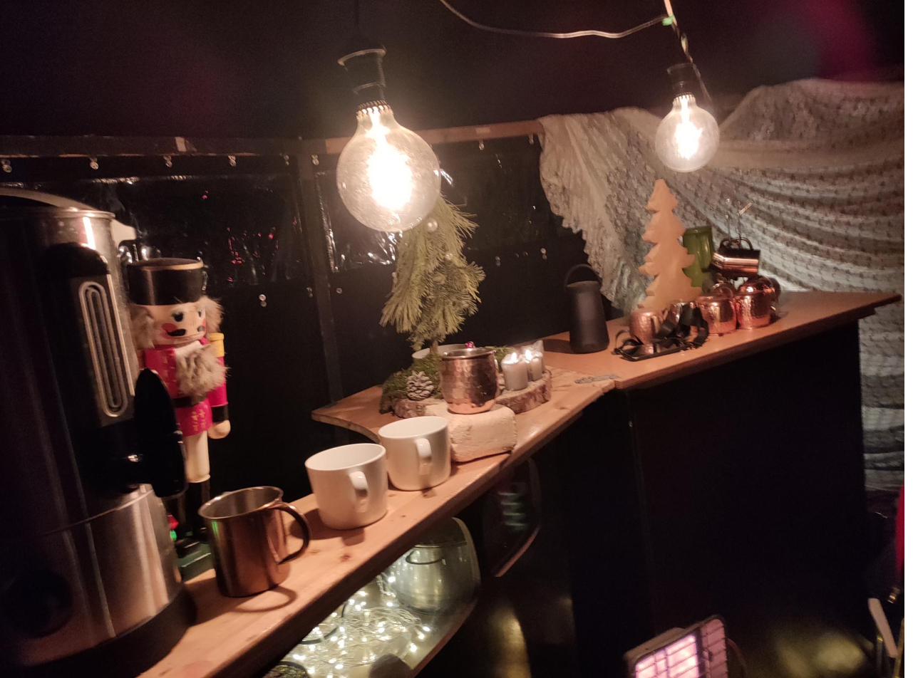 Weihnachtlich dekorierte Bar-Jurte mit Lichterketten und Kupfertassen als Stand für den Weihnachtsmarkt